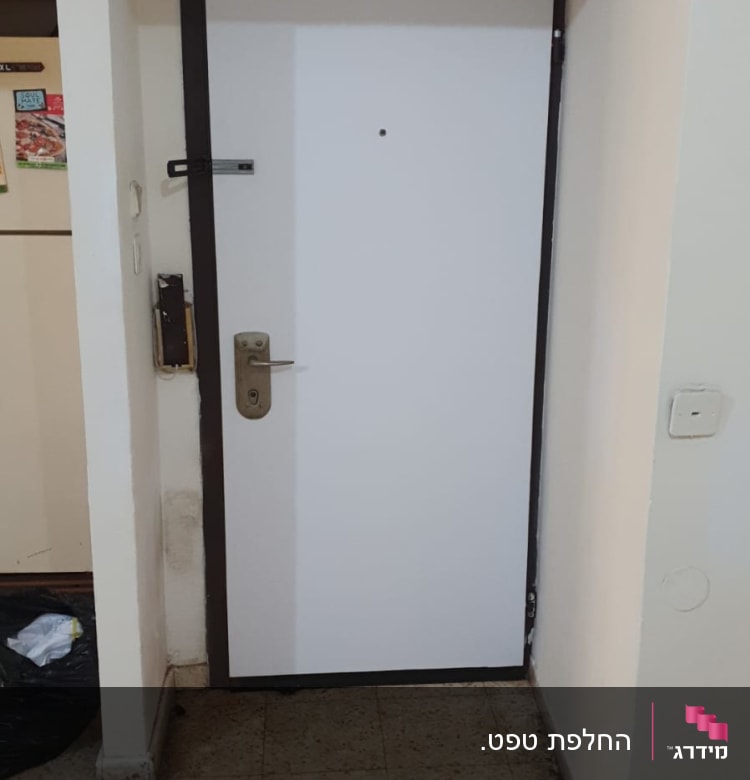 דלת לבנה עם ידית מתכת במסגרת כהה